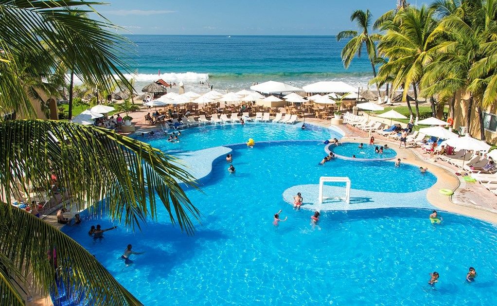 A pool with people swimming in it and some umbrellas