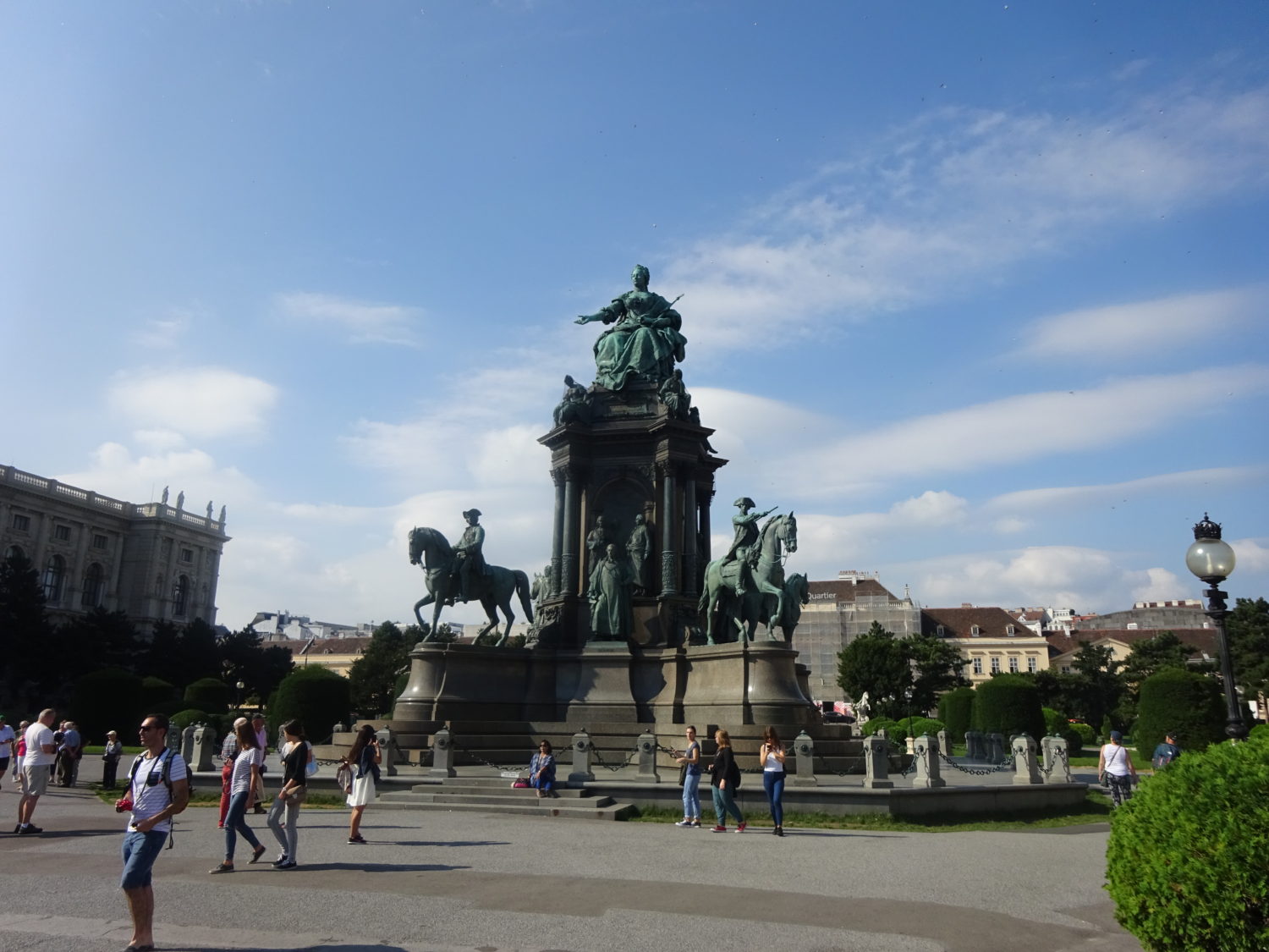 A group of people walking around in front of a statue.