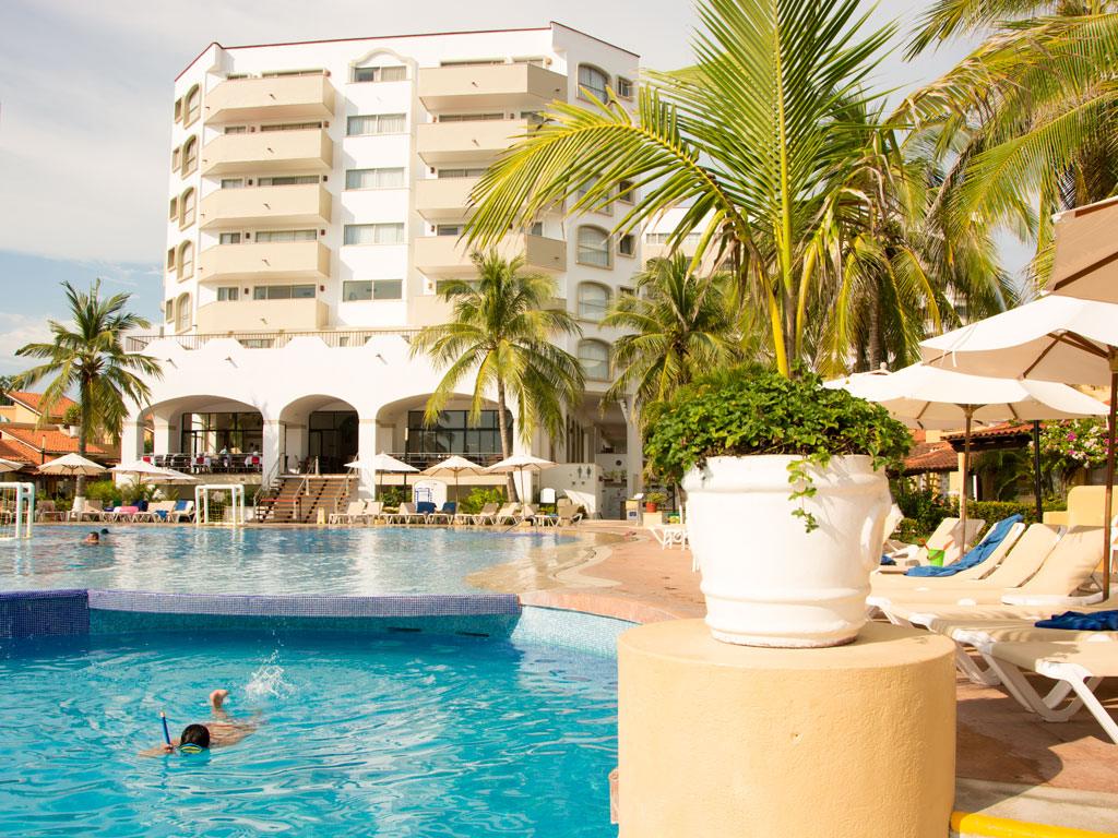 A pool with people swimming in it and palm trees