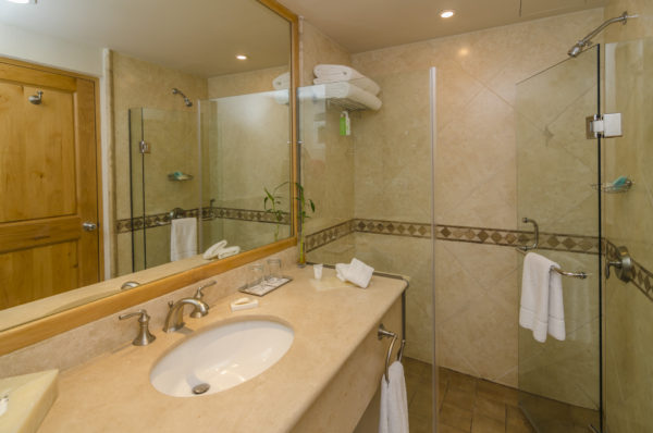 A bathroom with a sink, mirror and shower.