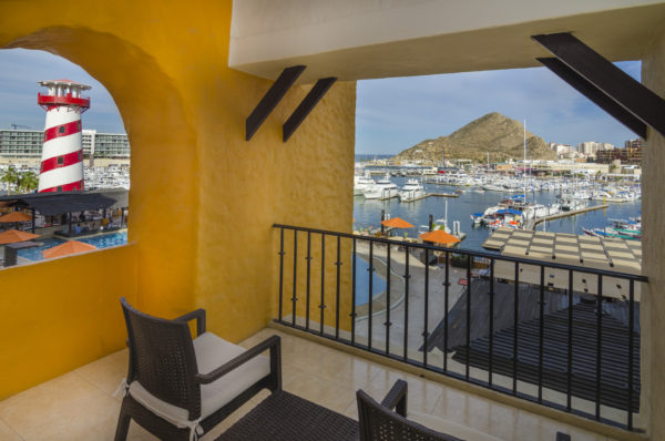 A balcony with chairs and tables overlooking the water.