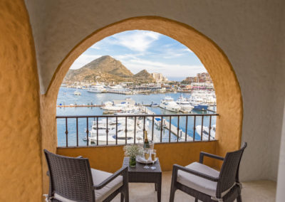 A balcony with chairs and tables overlooking the water.