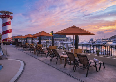 A row of chairs and umbrellas on the side of a pool.